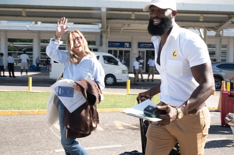 Driver and happy tourist waving outside the airport