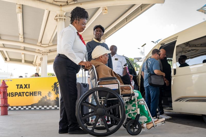 Staff assisting elderly passenger in wheelchair